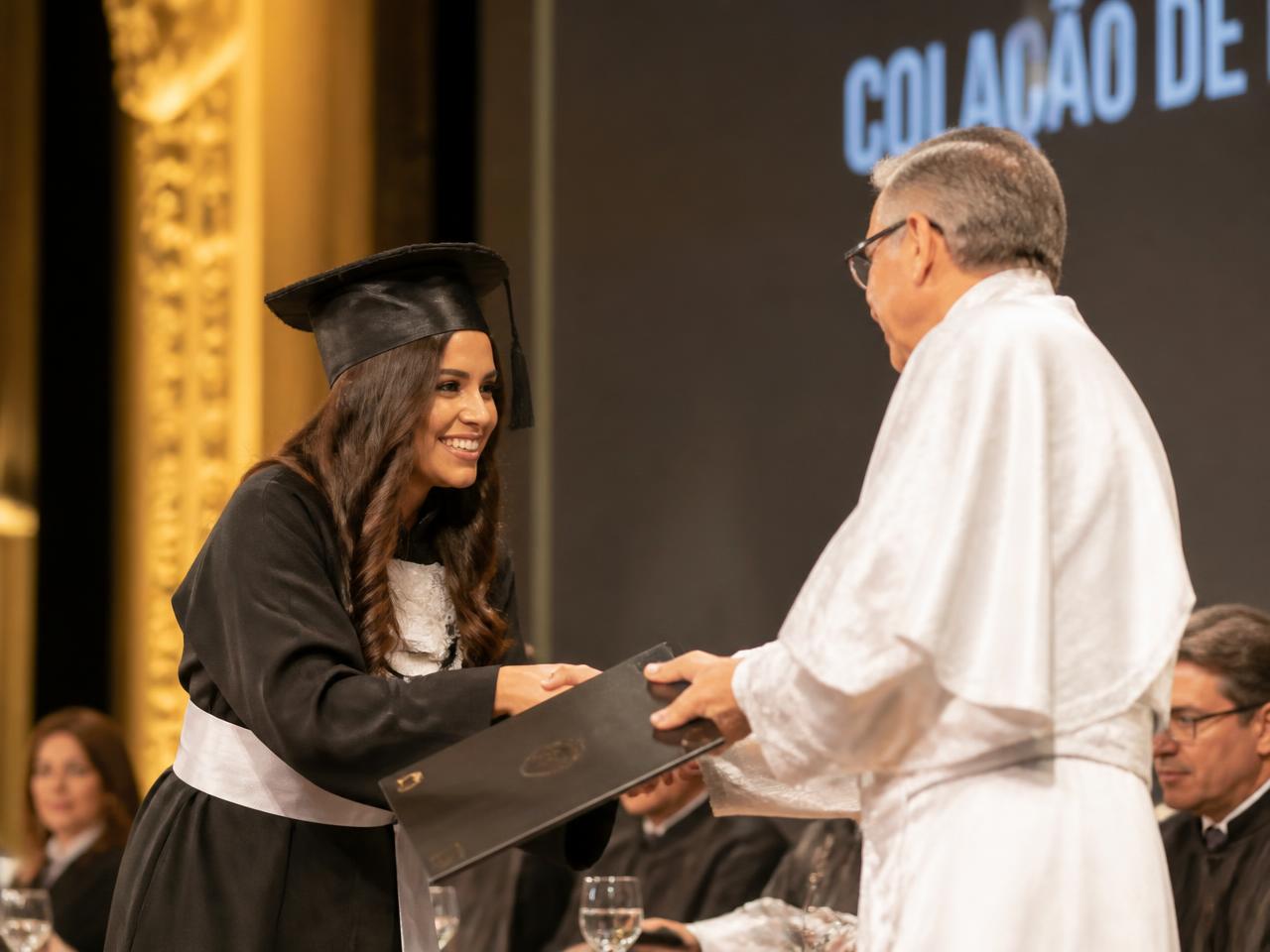 Formanda recebendo o diploma no palco